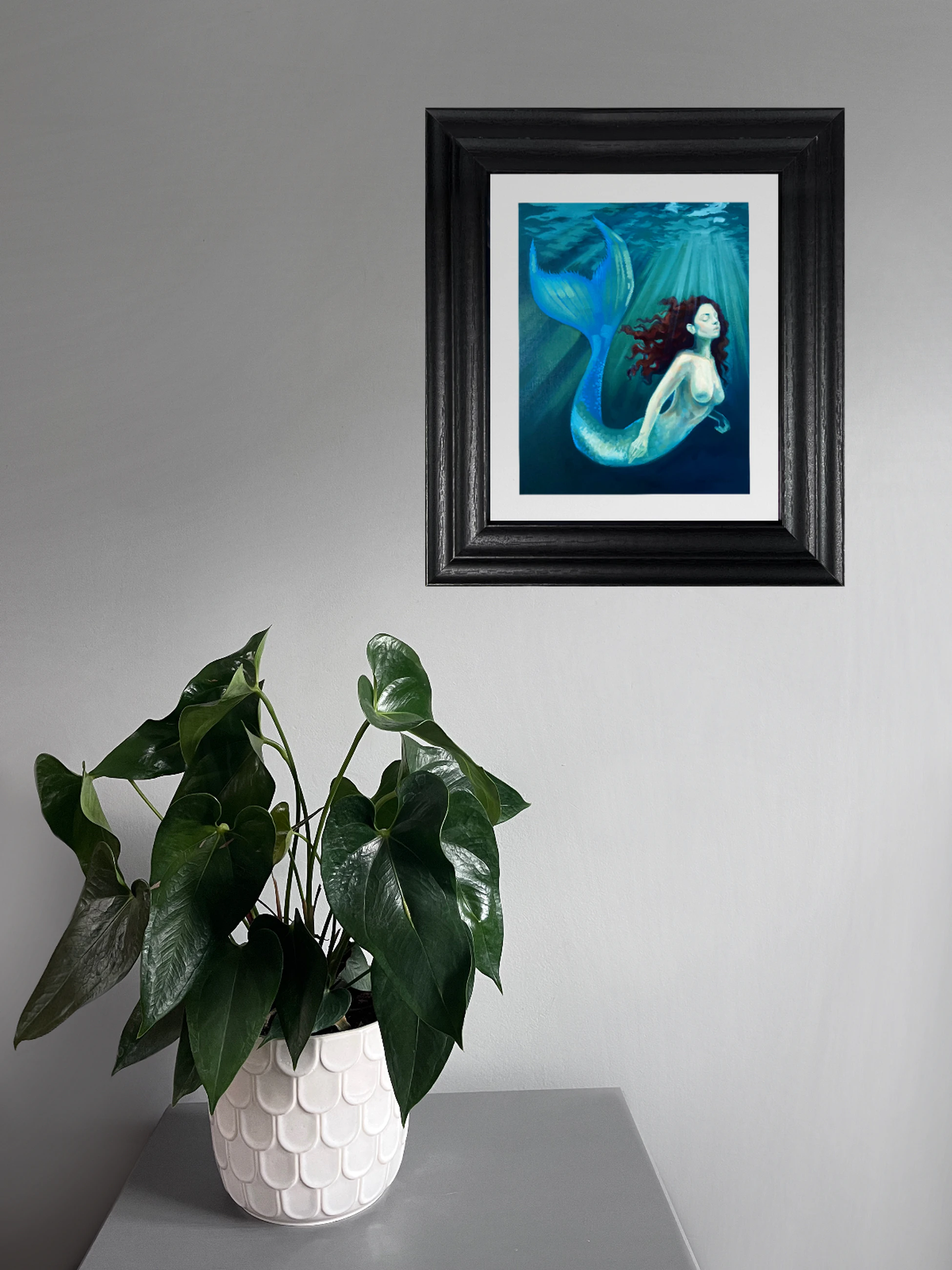 Mermaid with closed eyes drifting underwater in turquoise light, her body and sweeping tail surrounded by water
